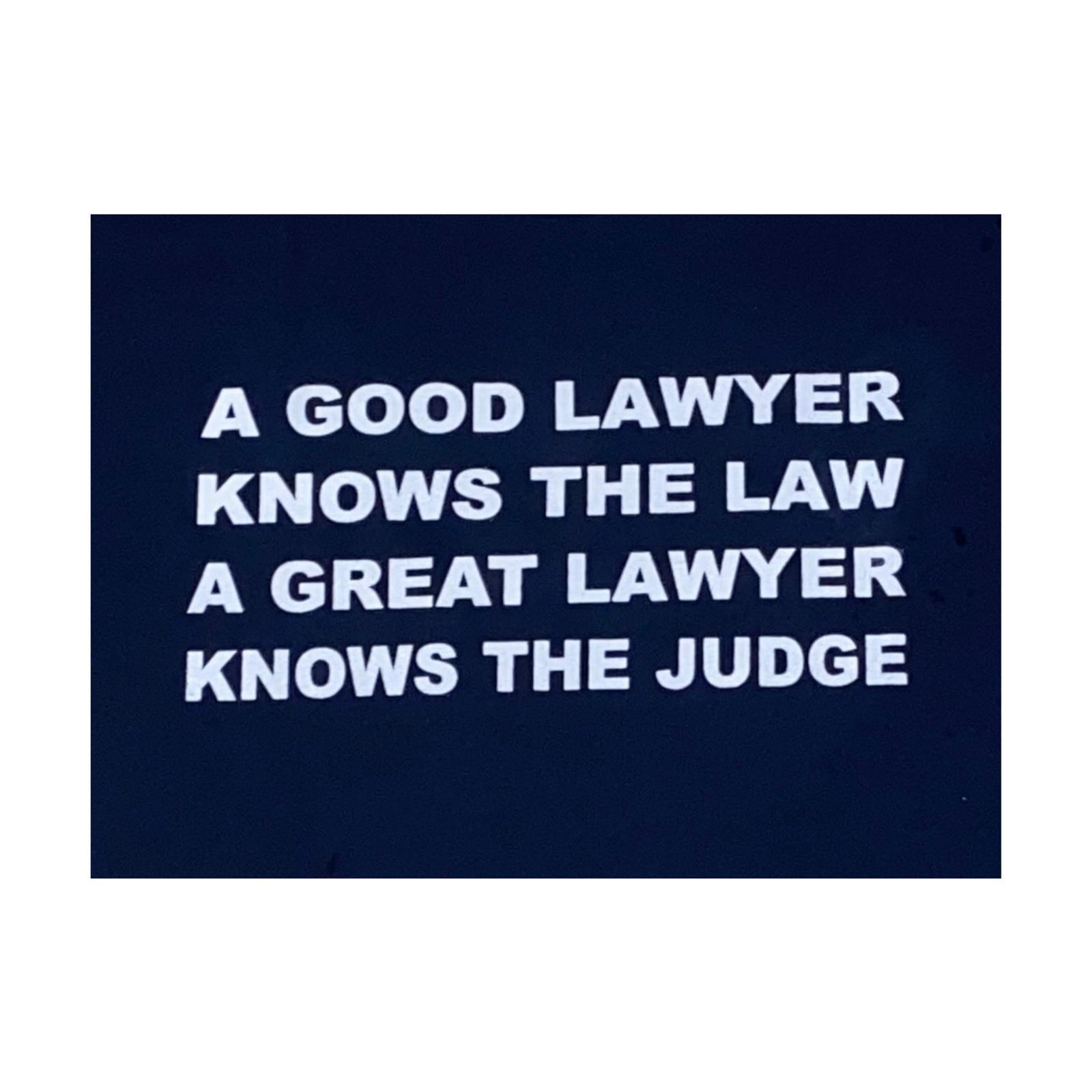 Navy blue sign with lawyer joke on white letters